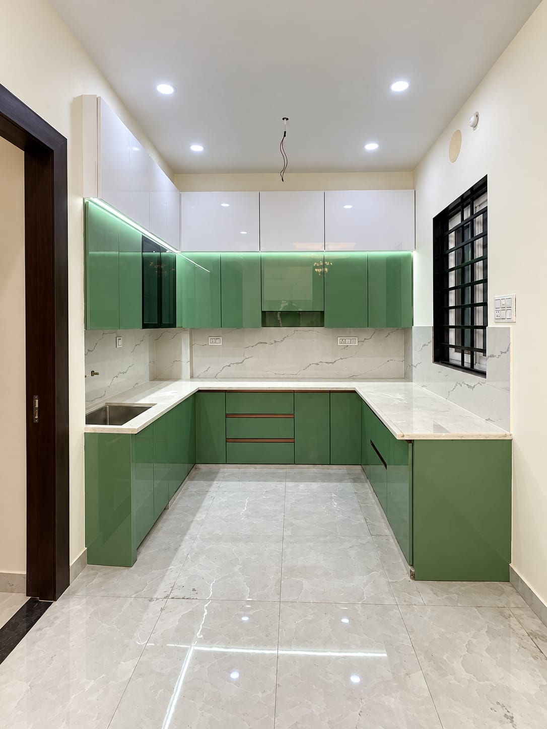 Contemporary U-shaped modular kitchen with sage green cabinets and profile lighting