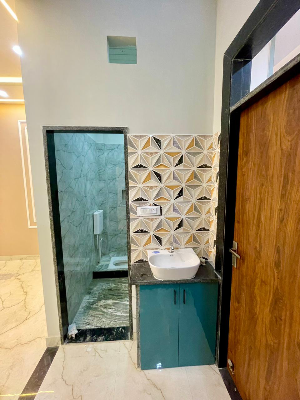 Vanity sink station with 3D prism ceramic tiles, turquoise vanity cabinet, and adjacent bathroom doorway in granite framing