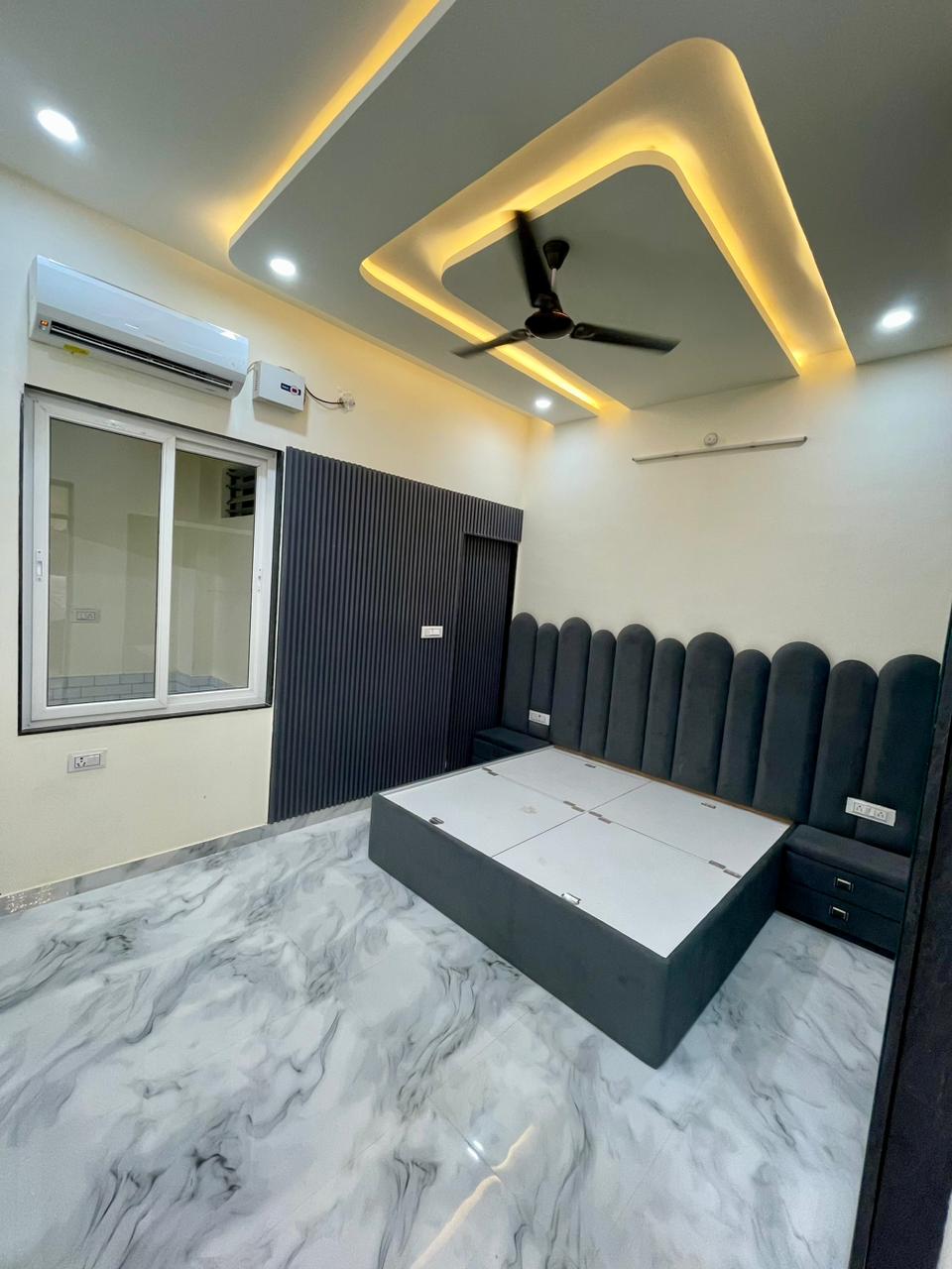 Luxury master bedroom featuring vertical charcoal fluted accent wall, custom scalloped velvet upholstered bed with hydraulic storage, and geometric false ceiling