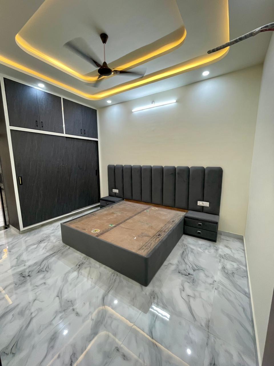 Master bedroom layout with upholstered headboard, dual integrated nightstands, dark sliding wardrobe, and warm cove ceiling
