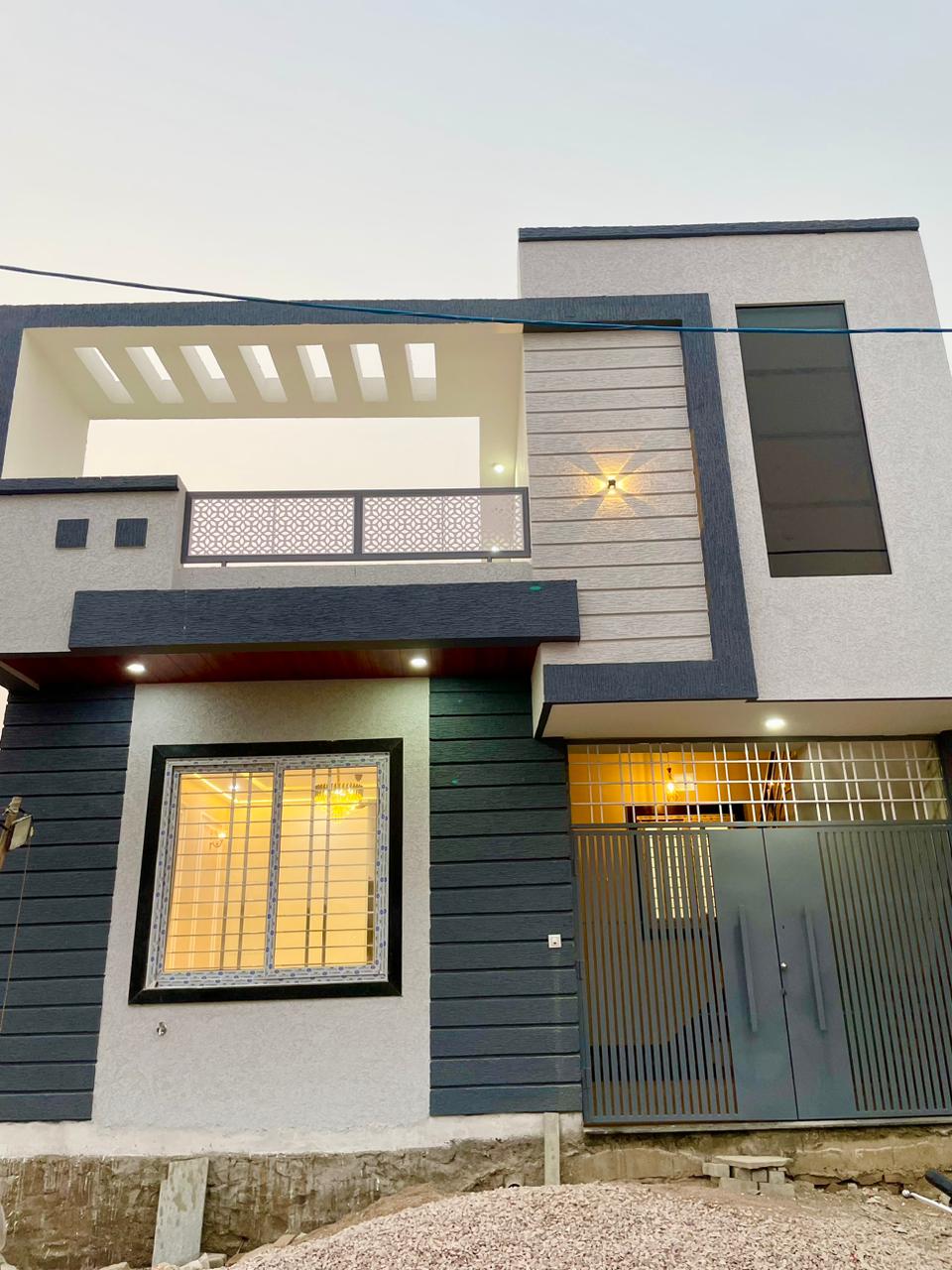 Modern residential villa front facade elevation with charcoal grooved panels, CNC geometric balcony railing, and exterior wall lighting