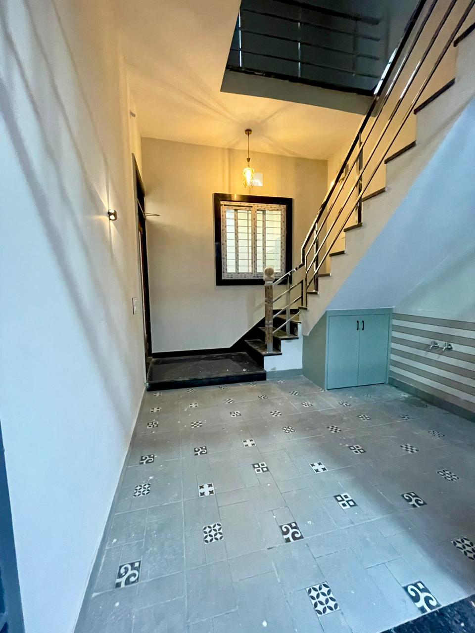 Covered stilt parking and entrance staircase with non-slip flooring, under-stair storage, and stainless steel railings