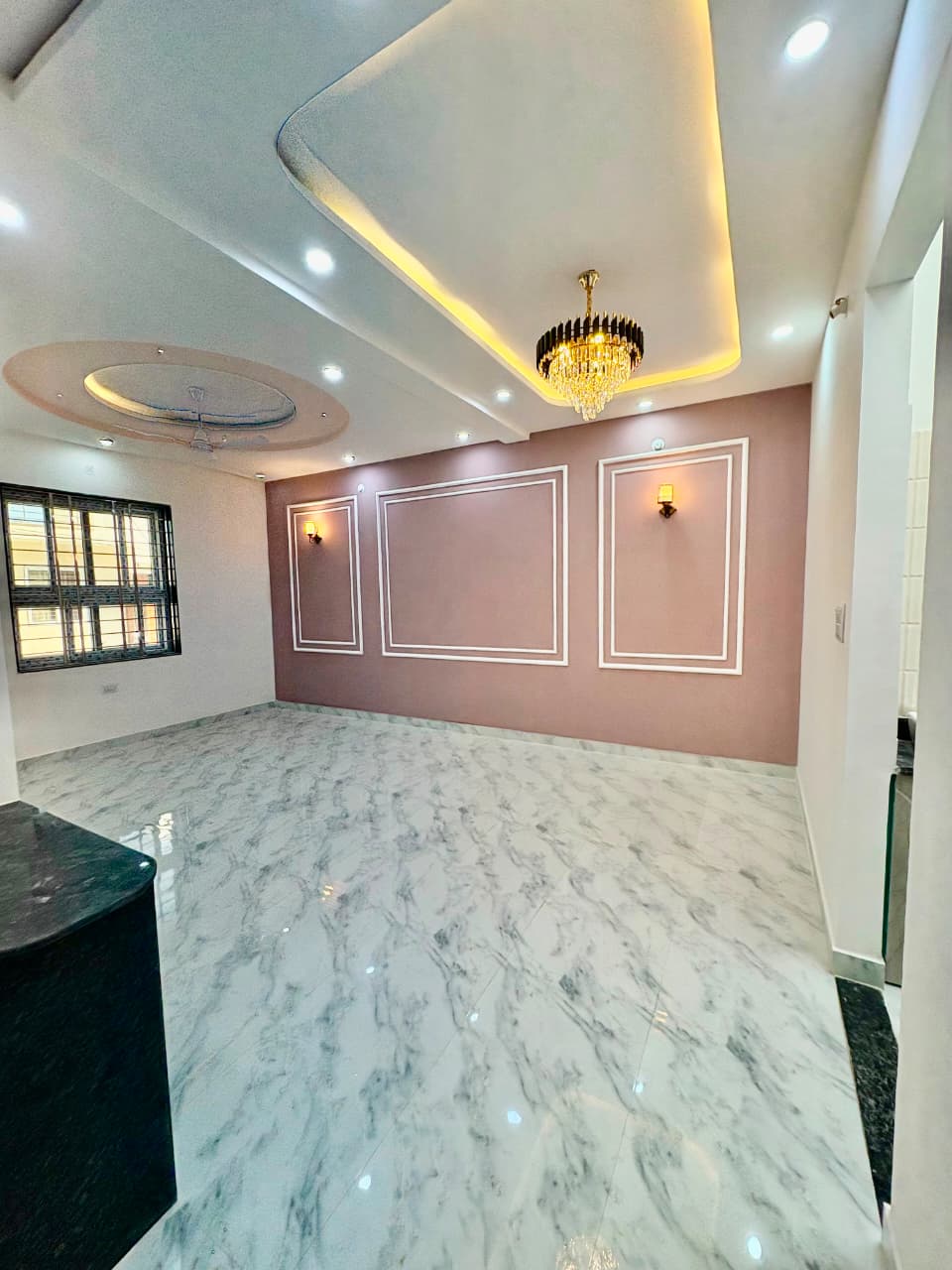 Elegant formal living hall showcasing neoclassical French wall mouldings, twin warm sconce lights, and crystal chandelier