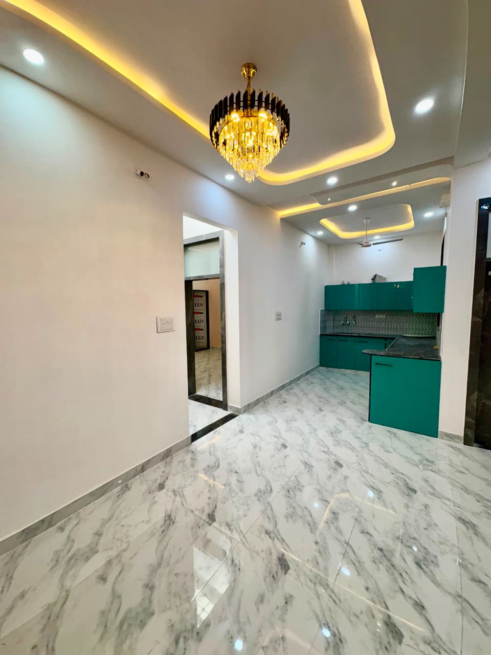Open-concept dining and living space featuring a luxury crystal chandelier and seamless access to modular kitchen