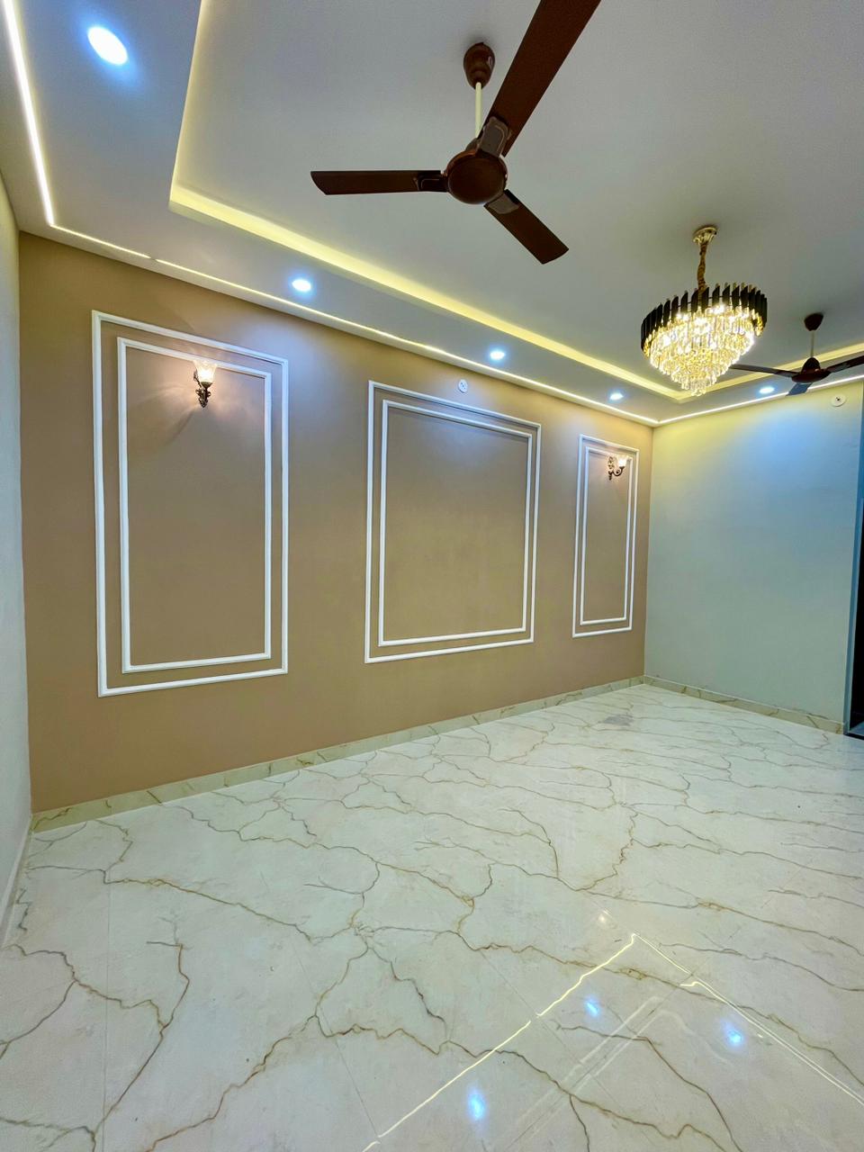 Grand formal living hall with classical boiserie wall trims, dual chandeliers, warm cove lighting, and gold veined marble tiles