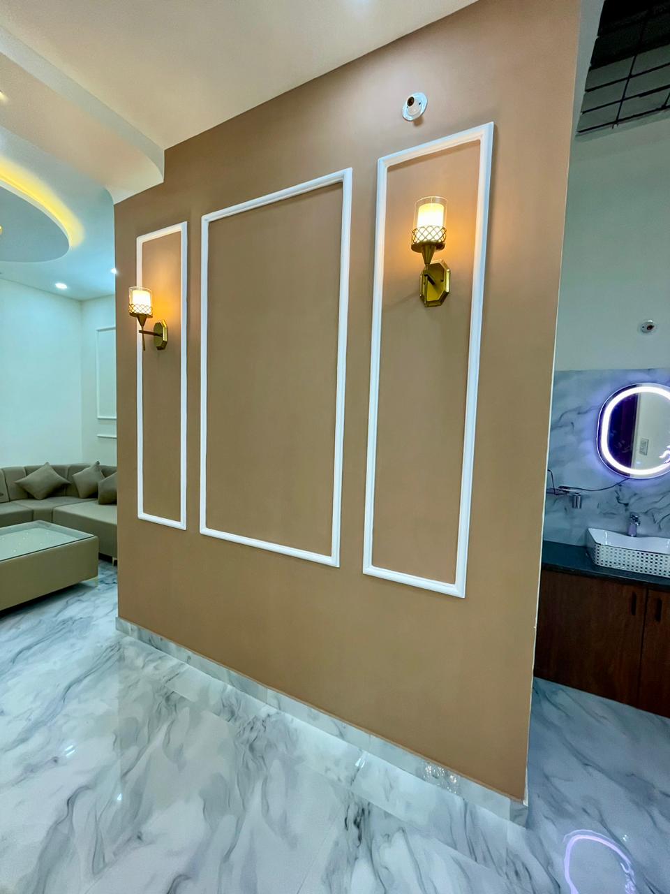 Warm terracotta feature wall highlighted with white picture-frame mouldings and brass finish luxury sconce lighting